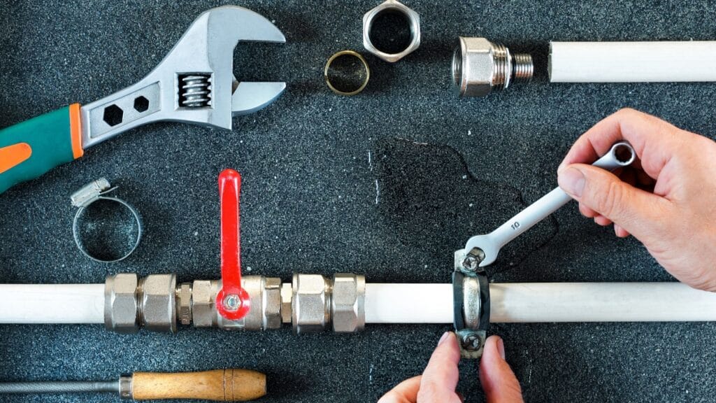 Plumber repairing a pipe valve with an adjustable wrench in Rockledge