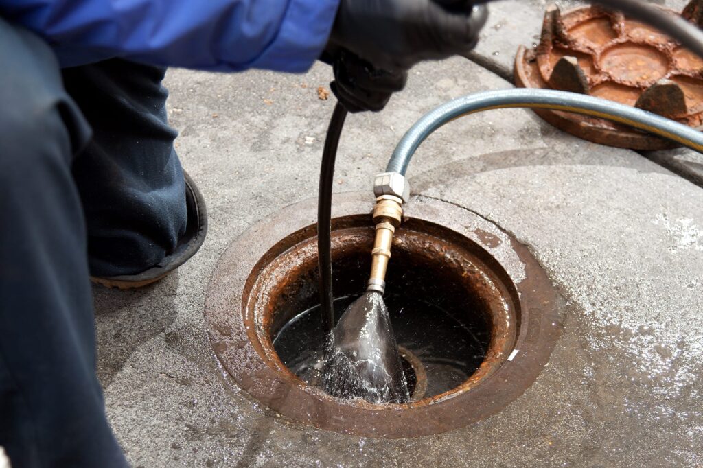 Plumber hydro jetting a sewer line through a manhole in Rockledge