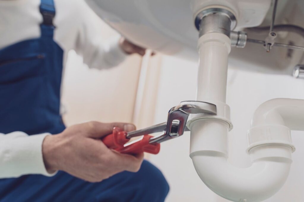 Plumber repairing a white drain pipe beneath a sink in Rockledge