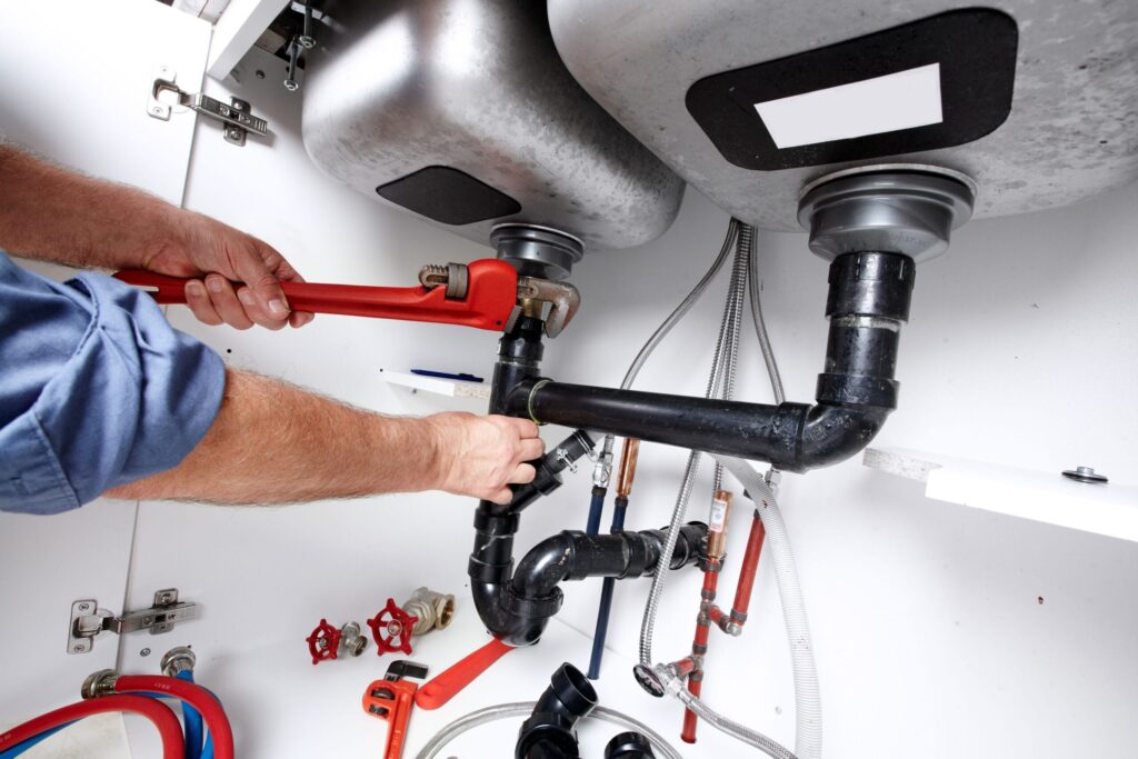 Plumber repairing drain pipes beneath a kitchen sink in Rockledge