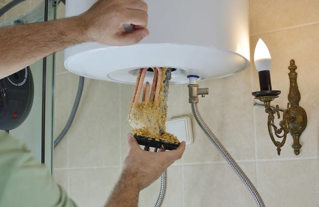 Technician removing mineral buildup from a water heater in Rockledge
